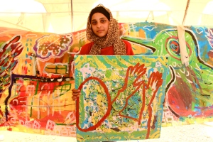 A young Syrian shows the work she's created in an art workshop