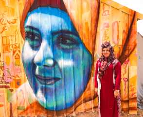 Azraq Syrian Refugee Camp, Jordan 2017: Dareen, a participant in our Azraq Camp project, poses in front of a portrait of her.