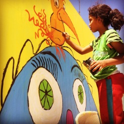 A Syrian girl painting a mural in Za'atari refugee camp